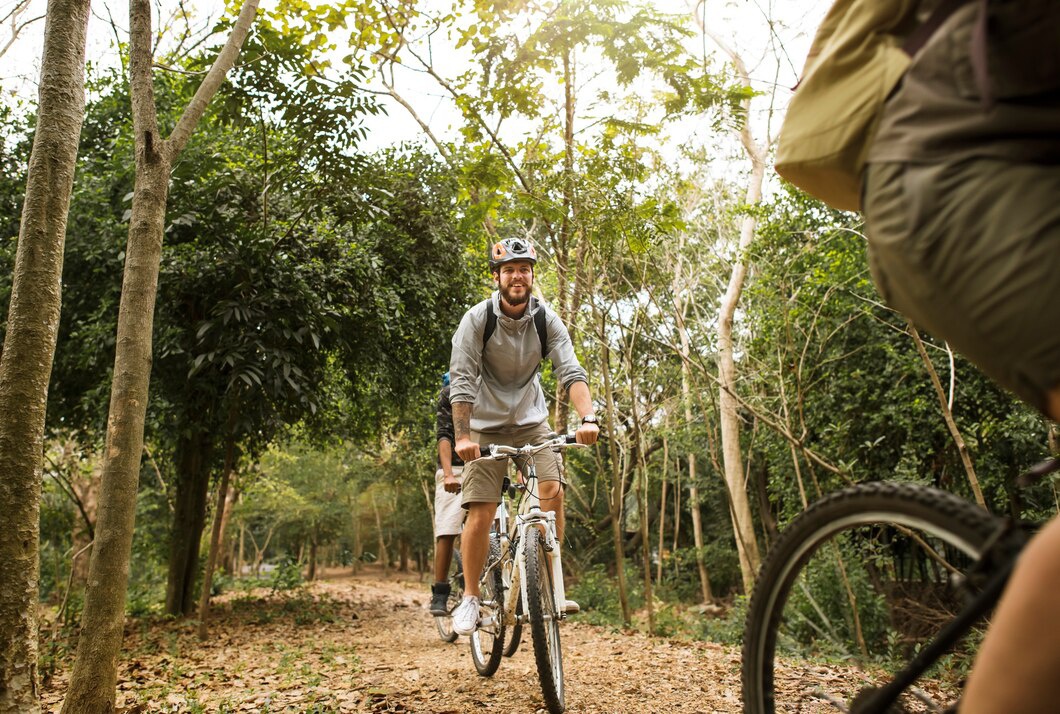 Two cyclists navigate a gravel path surrounded by lush greenery and trees in a tranquil outdoor setting.